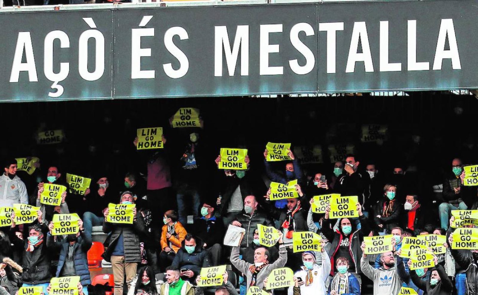 Aficionados en Mestalla levantando pancartas amarillas con el lema «Lim go home» bajo el cartel «Açò és Mestalla»